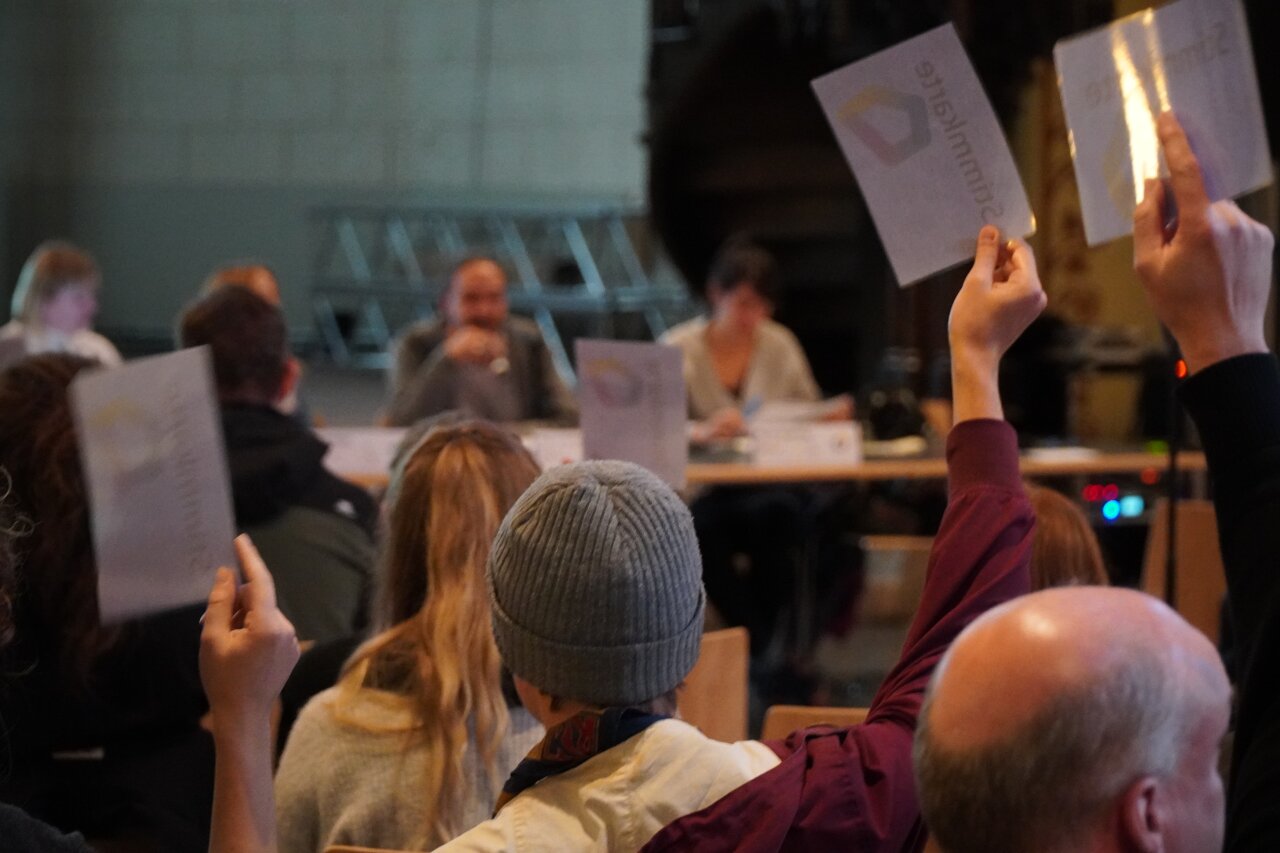 Viele Hände mit Stimmkarten des Stadtjugendrings.